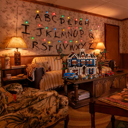 Brick-built Creel House from Stranger Things in an 80s living room with the painted alphabet wall and Christmas lights